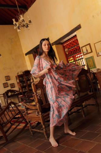 a woman in a dress standing next to a chair at CASA SINNING-año1637 in Mompos
