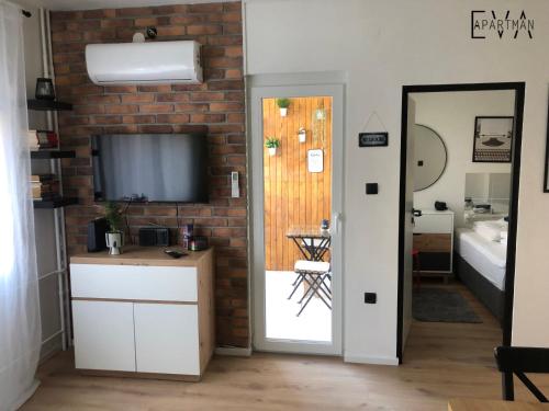 a living room with a television on a brick wall at Apartman EVA - Dugo Selo / Zagreb in Dugo Selo