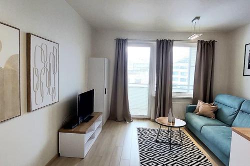 a living room with a blue couch and a tv at Apartmán Soul 200 m do centra s private parking in Košice