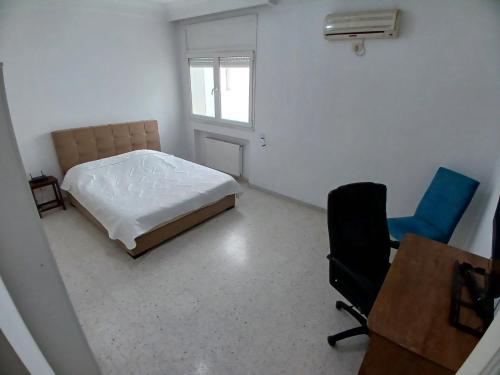 een slaapkamer met een bed, een bureau en een stoel bij calm inn Centre Urbain Nord in Ariana