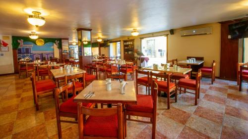 a restaurant with wooden tables and red chairs at Hotel del Gobernador in Mérida
