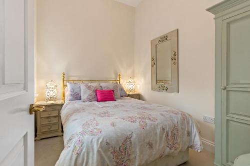 a white bedroom with a bed with a pink pillow at Bryn Y Mor - Tenby Apartment Sea Views in Tenby