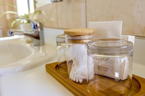 a glass jar on a wooden tray next to a sink at Coleraine Suites & Apartments in Greymouth