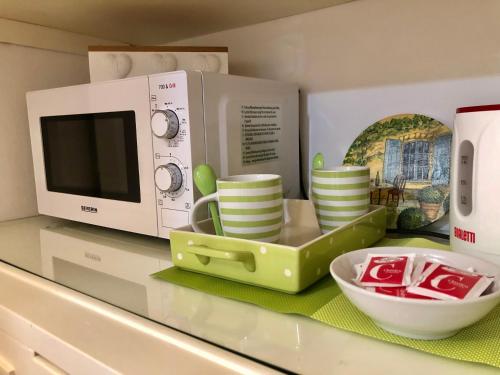 a kitchen counter with a microwave and a tray of dishes at G&G ROOMS in Palermo