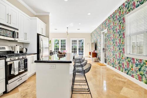 una cocina con armarios blancos y una isla de cocina con taburetes en Light Filled Home Walk to Wilton Dr - Hot Tub!, en Fort Lauderdale
