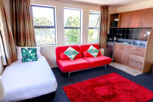 a living room with a red couch and a red rug at Coleraine Suites & Apartments in Greymouth