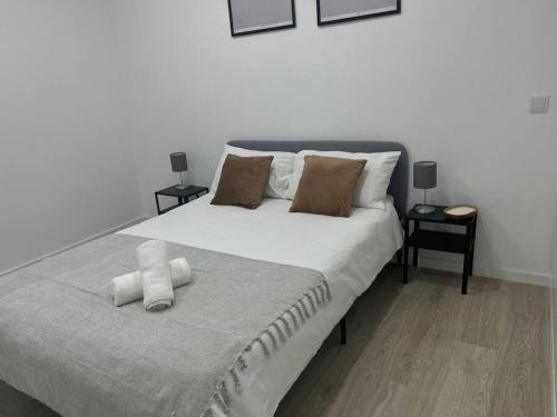a bedroom with a large white bed with two pillows at Bright and modern flat with air-con and free parking in Moita