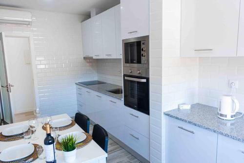 a kitchen with white cabinets and a stove top oven at Bright and modern flat with air-con and free parking in Moita