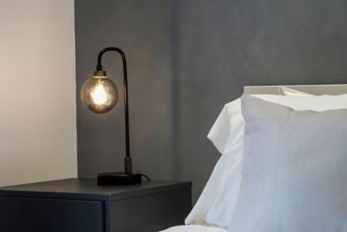 a lamp on a night stand next to a bed at Stylish Apartment - Close to the City Centre - Free Parking, Fast Wi-Fi and Smart TV with Netflix by Yoko Property in Aylesbury