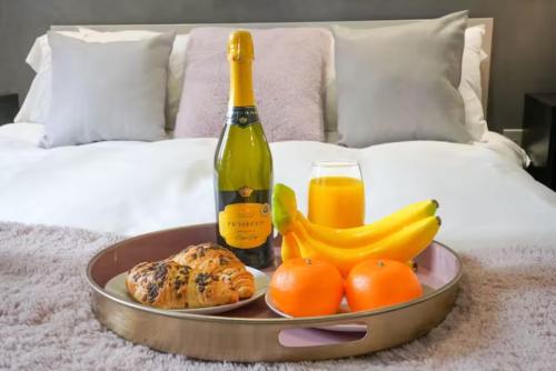 a tray with a bottle of wine and fruit on a bed at Stylish Apartment - Close to the City Centre - Free Parking, Fast Wi-Fi and Smart TV with Netflix by Yoko Property in Aylesbury
