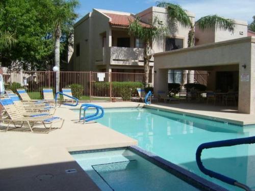 a swimming pool with lounge chairs and a house at Heated Community Pool-Quiet Community-Top Flr Unit in Mesa