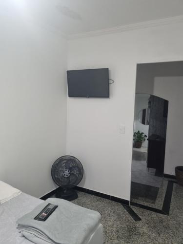 a bedroom with a tv on a white wall at Hostel Anprado in Guarulhos