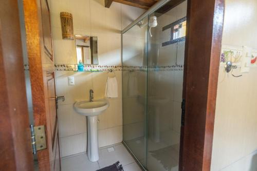 a bathroom with a sink and a glass shower at Vila Guaiamum in Cumuruxatiba