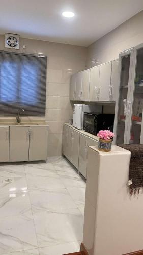 a large kitchen with white cabinets and a counter with flowers at شقة مكونة من صالة وغرفة نوم in Al Hofuf