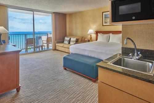 a hotel room with a bed and a kitchen with a sink at Waikiki Resort Hotel in Honolulu