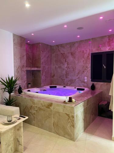 een grote badkamer met een groot bad met paarse verlichting bij Suite Marajah in Le Pontet