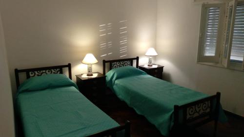 two beds in a room with green sheets and lamps at DC Alquileres Temporarios in Santa Fe