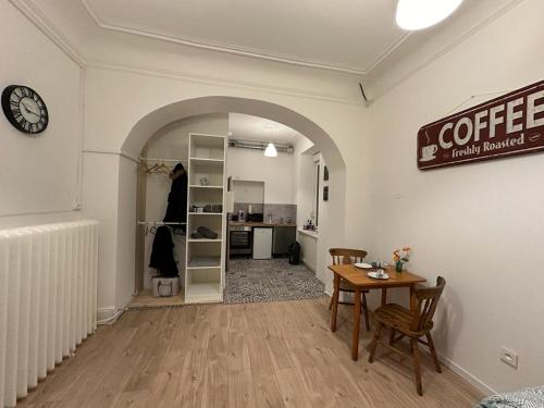 un salon avec une table et une chambre avec une horloge dans l'établissement Le Petit Café - Centre ville, parking gratuit, à Mulhouse