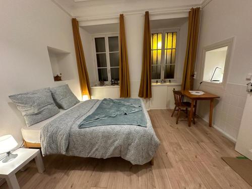 une chambre avec un lit et une table et deux fenêtres dans l'établissement Le Petit Café - Centre ville, parking gratuit, à Mulhouse