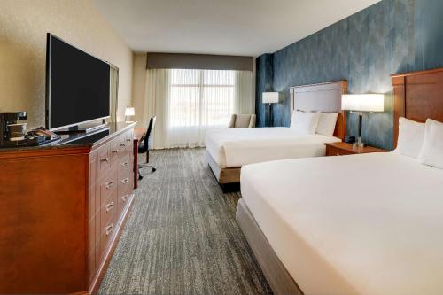 a hotel room with two beds and a flat screen tv at Drury Plaza Hotel Denver Westminster in Westminster