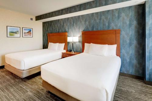 two beds in a hotel room with white sheets at Drury Plaza Hotel Denver Westminster in Westminster