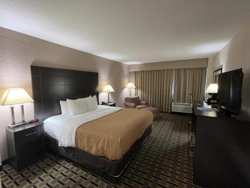 シンシナティにあるQuality Inn & Suites Cincinnati Downtownの大型ベッドとテレビが備わるホテルルームです。