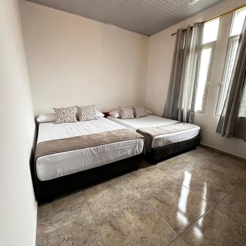 two beds in a room with two windows at Apartamento Familiar Buga - Basílica señor de los milagros N1 in Buga