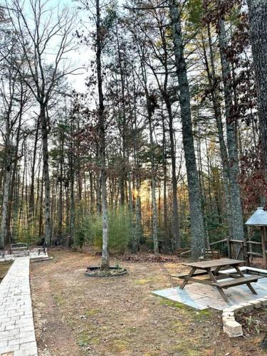 a picnic table in the middle of a forest at Beautiful & peaceful cabin w/ deck garden & fire-pit in Murphy
