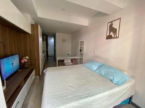a bedroom with a bed and a flat screen tv at Apartamento grande Soho 39 in Bogotá
