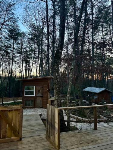 a wooden deck with a cabin in the woods at Beautiful & peaceful cabin w/ deck garden & fire-pit in Murphy