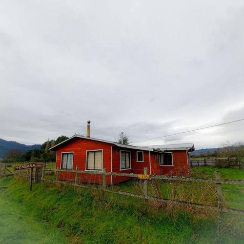 una casa roja en medio de un campo en Acogedora Cabaña, en Riñinahue