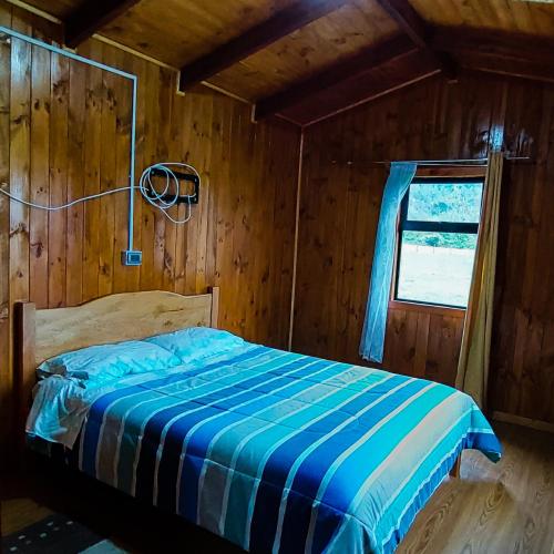 1 dormitorio con 1 cama en una cabaña de madera en Acogedora Cabaña, en Riñinahue