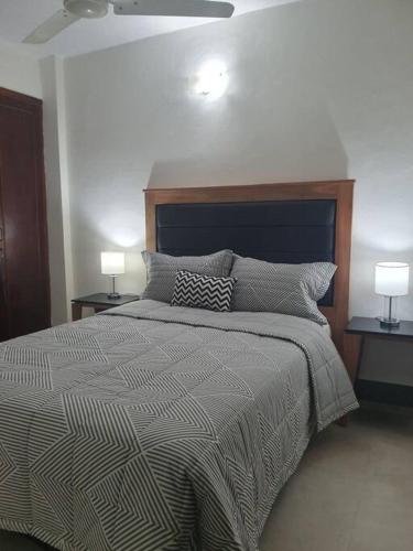 a bedroom with a bed with two lamps on two tables at Departamento Nuevo, Asunción in Asunción