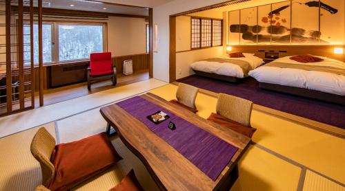 1 Schlafzimmer mit 2 Betten, einem Tisch und Stühlen in der Unterkunft Hotel Taisetsu Onsen&Canyon Resort in Kamikawa