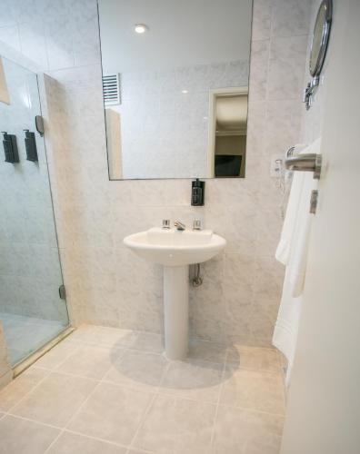 a bathroom with a sink and a mirror and a shower at Regency Park Hotel in Rio de Janeiro