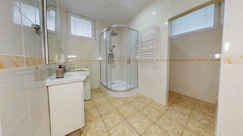uma casa de banho com um chuveiro e um lavatório. em Apartmán Harmónia, Bardejovské kúpele em Bardejovské Kúpele