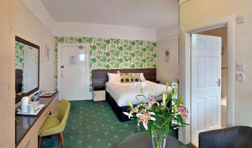 une chambre d'hôtel avec un lit et un vase de fleurs dans l'établissement Cavendish Central Bournemouth, à Bournemouth