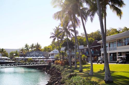 a bridge over a river with palm trees and buildings at Palm Bungalows in Hamilton Island