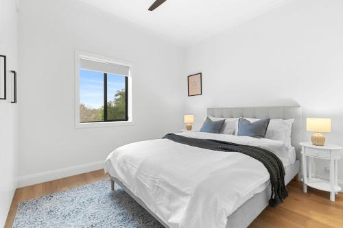 a white bedroom with a large bed and a window at Hamilton Lodge in Sydney