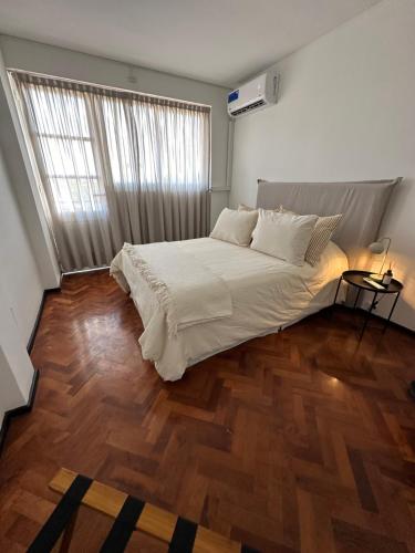 een slaapkamer met een groot bed en een houten vloer bij Avenida Colon Trendy APT in Mendoza
