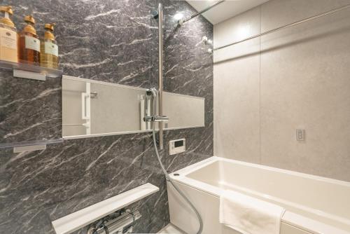 a bathroom with a shower and a tub and a sink at 谷町君ホテル　難波80 in Osaka