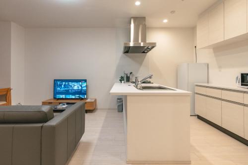 a kitchen with a couch and a sink and a refrigerator at 谷町君ホテル　難波80 in Osaka
