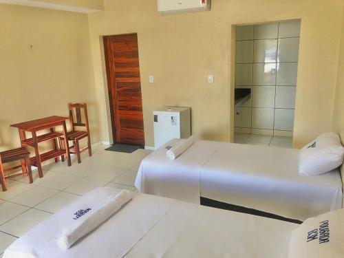 a room with two beds and a table and a chair at Pousada B3M in Itarema