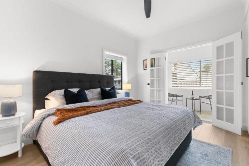 a white bedroom with a large bed with a blue rug at Hamilton Lodge Apartments by Urban Rest in Sydney