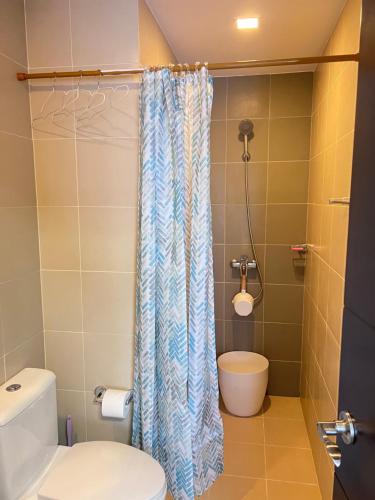 a bathroom with a toilet and a shower curtain at Comfy studio room in Bacolod