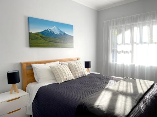 a bedroom with a bed with a mountain picture on the wall at Huatoki Hideaway Peaceful Central Location in New Plymouth