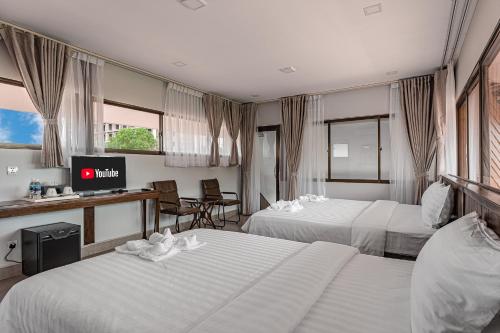 a hotel room with two beds and a television at Sandy Residence Sihanoukville in Sihanoukville