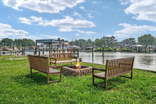 two benches sitting next to a fire pit next to the water at Waterfront Bliss- Ultimate Tilghman Retreat home in Tilghman