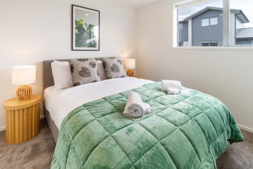 - une chambre avec un grand lit et une couverture verte dans l'établissement Upper Riccarton dream - 2 bed 2 bath w/carpark, à Christchurch
