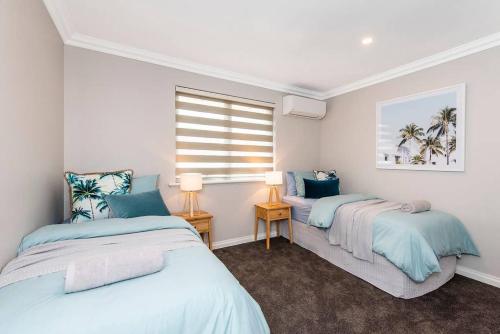 twee bedden in een kamer met een raam bij 7 Royal Family Kensington 4br 2bth in Perth